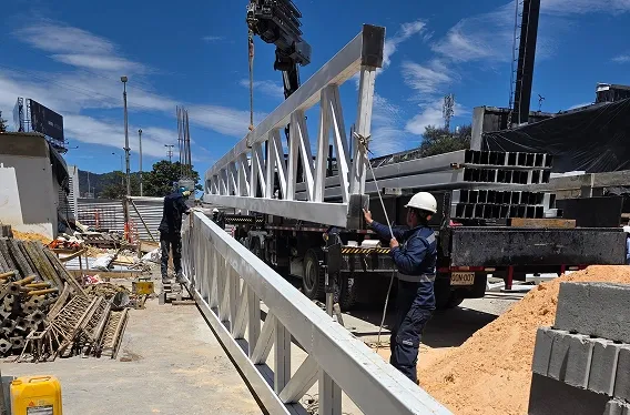 trabajadores izando una estructura metalica para cubierta standing seam con ayuda de una grua