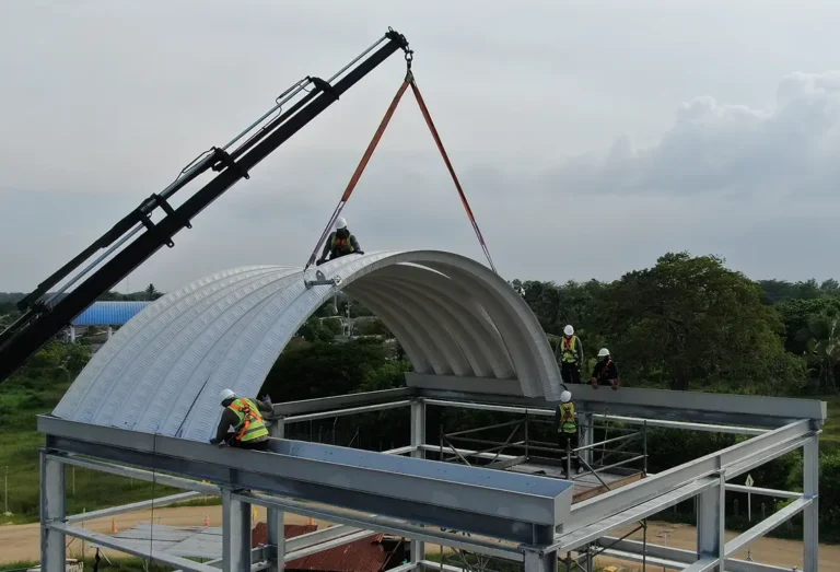 grua y trabajadores realizando el izaje y montaje de una cubierta autoportante en una estructura metalica